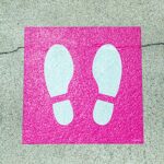 white and pink foot print signage on concrete surface