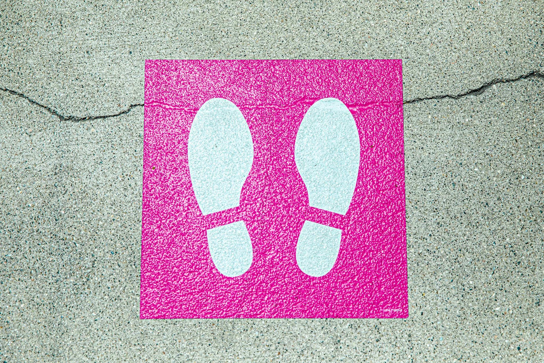 white and pink foot print signage on concrete surface